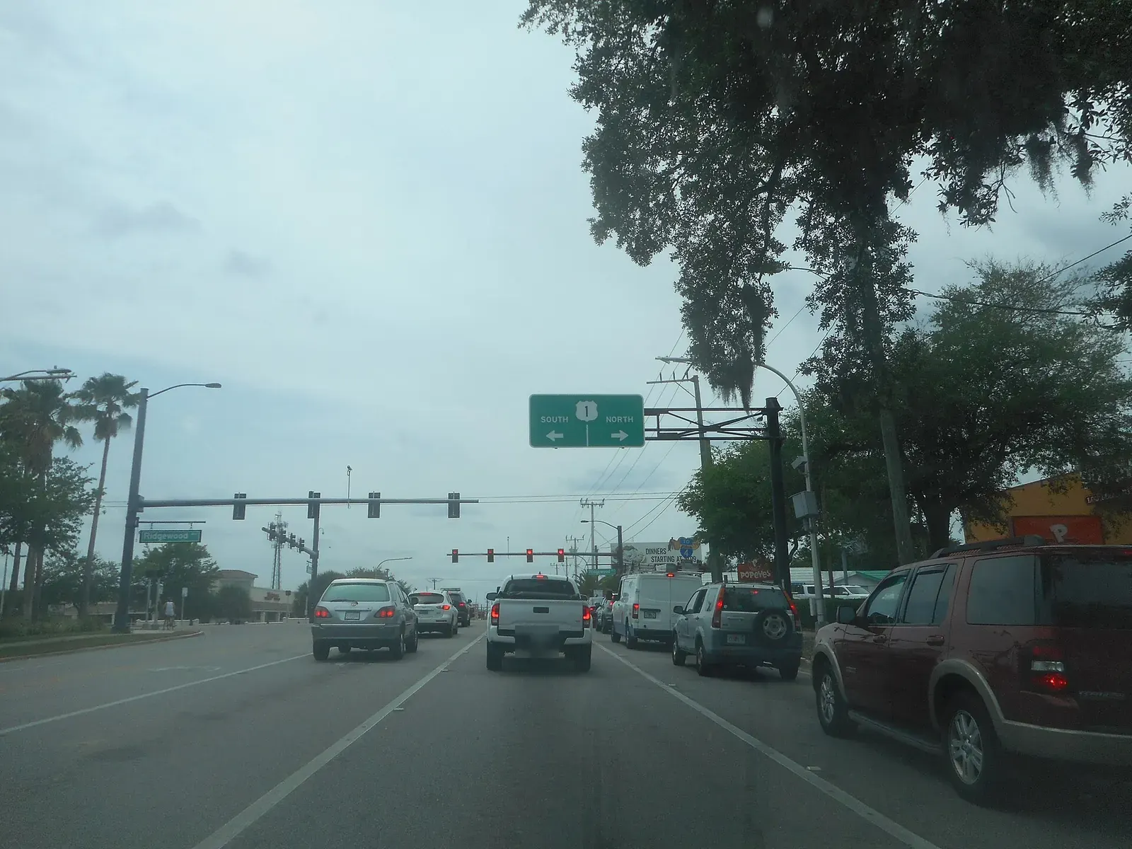 Cars queued on US 92 under traffic signals and an overhead US 1 sign
