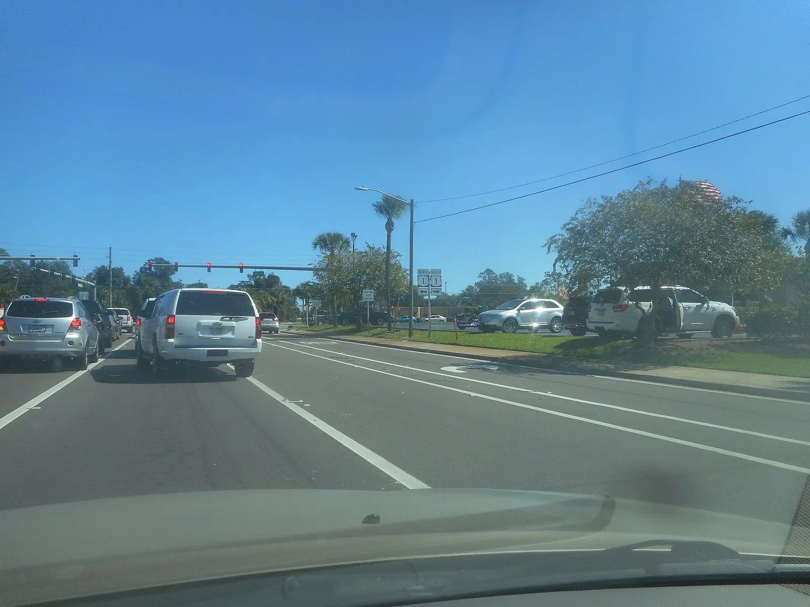 Driver's view of traffic queued on eastbound Indian River Boulevard at the US 1 intersection, with US 1 route signs and signals ahead