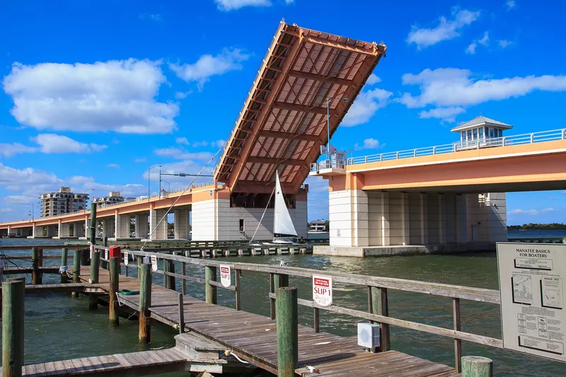North Causeway drawbridge span raised for a sailboat, seen from a wooden dock