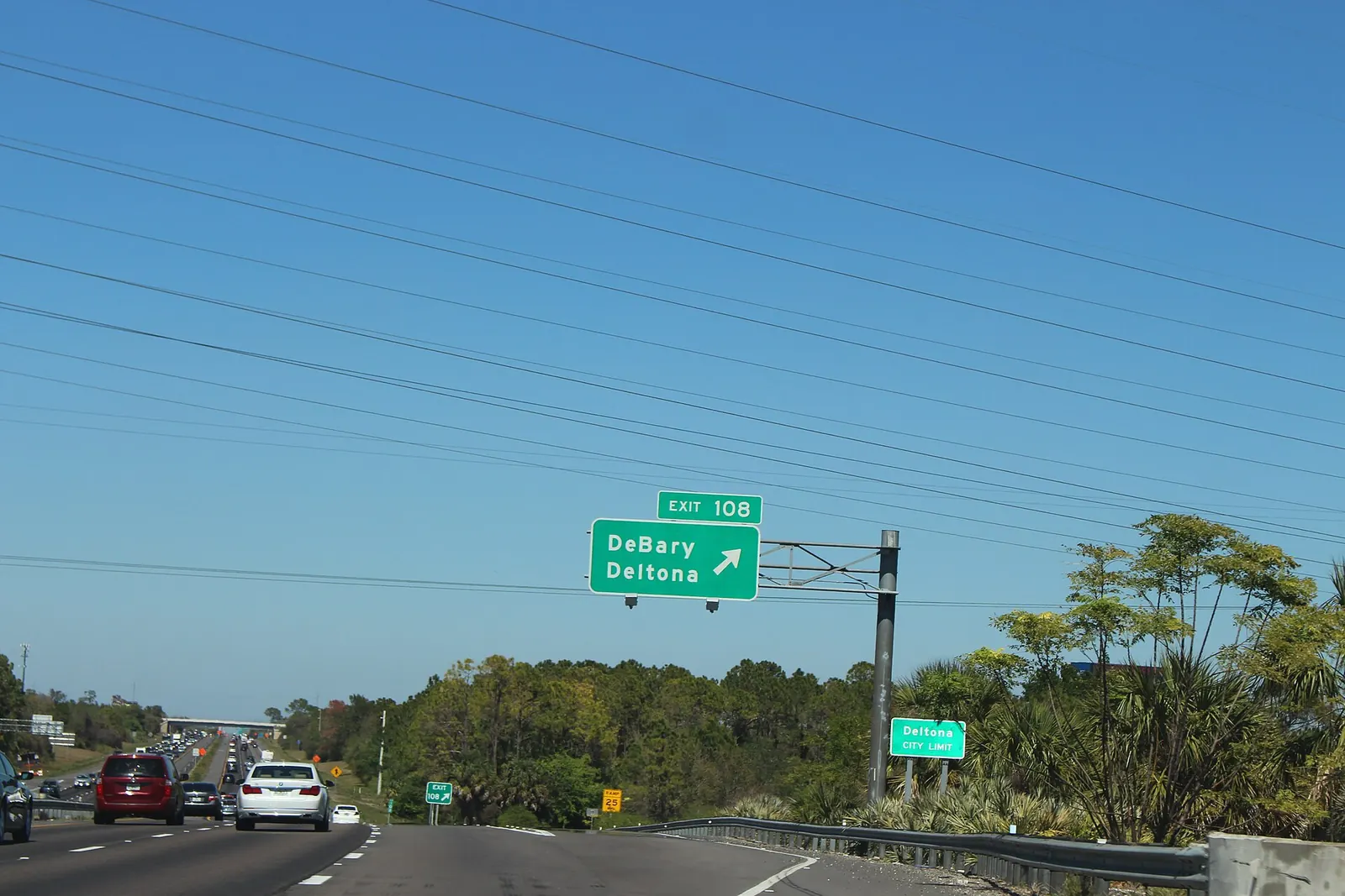 Busy interstate lanes with a green Exit 108 sign for DeBary and Deltona